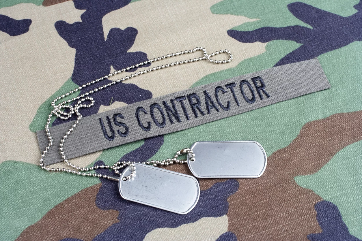 US CONTRACTOR branch tape and dog tags on woodland camouflage uniform demonstrating the importance of military contracting